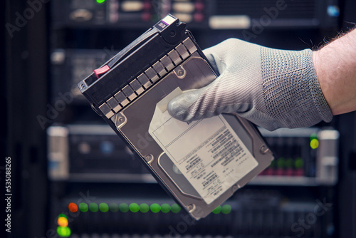 A hard disk for a raid in the hands of a man at a data storage server, close-up photo