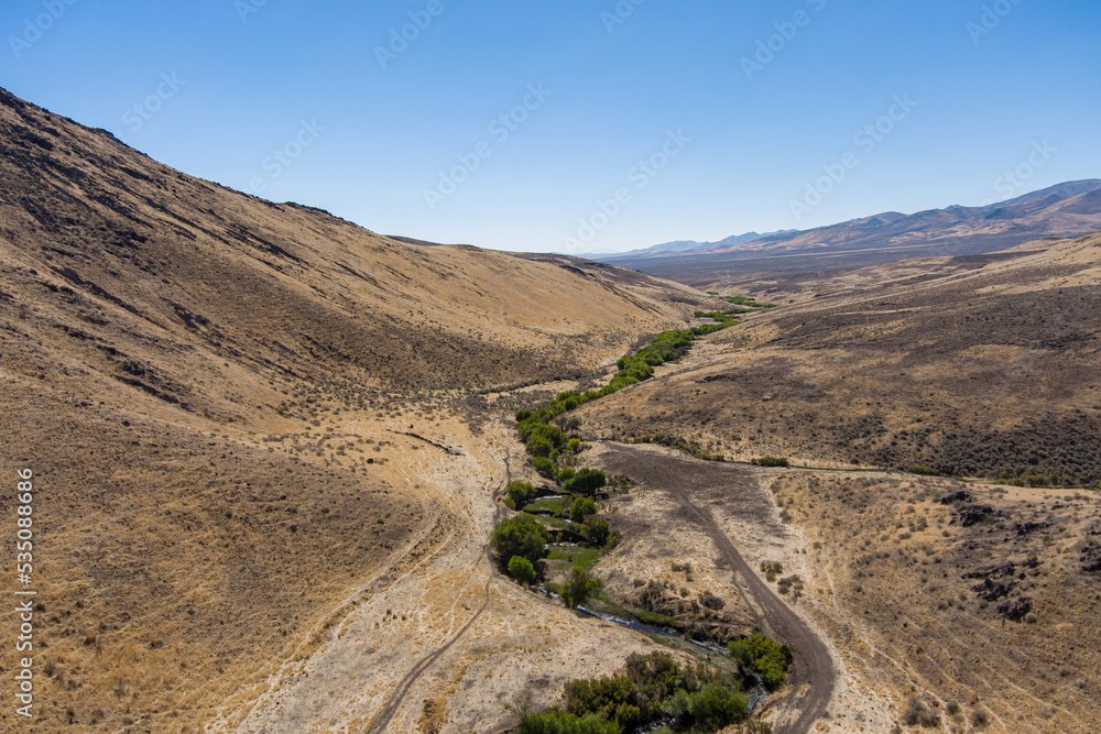 Aerial view of a road along a stream in an arid canyon in the northern Nevada desert.