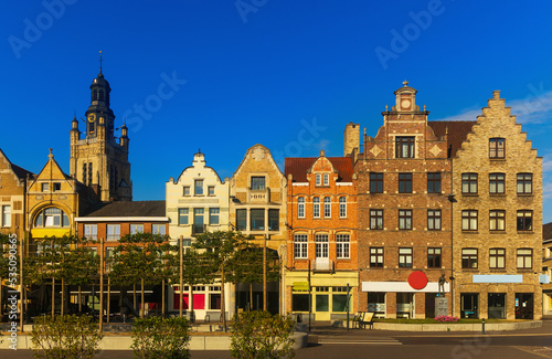 Scenic view of summer cityscape of Roeselare overlooking belfry of Saint Michael Church rising above typical Flemish style townhouses on central Grote Markt square on sunny day, West Flanders, Belgium