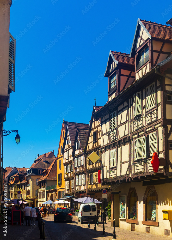 Traditional architecture of Colmar. View of medieval timber-framed townhouses in narrow cobblestone-covered streets in small French town on summer day