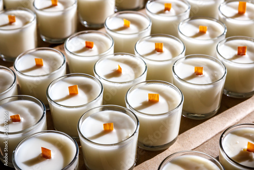 A row of scented candles illuminated by the bright sun stands on the table.