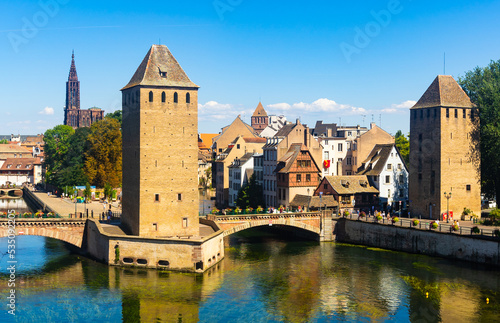 Picturesque Strasbourg cityscape overlooking medieval arched Ponts Couverts and watchtowers seen from viewing platform of Barrage Vauban on sunny summer day, France