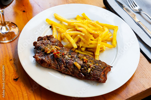 Spicy grilled veal tenderloin served on white plate with crispy French fries