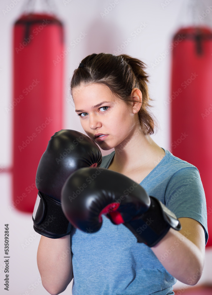 collected sportwoman in the boxing hall practicing boxing punches during training