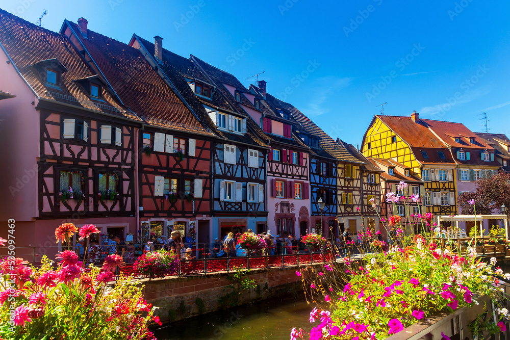 Picturesque summer view of Little Venice quarter in Colmar with small half-timbered houses located on banks of canal flowing through city center, France