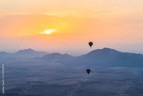 hot air balloon flying over the Moroccan desert and the atlas mountains at sunrise © Antoine