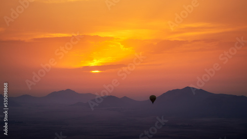 Photography hot air balloon flying over the Moroccan desert and the atlas mountains at sunri