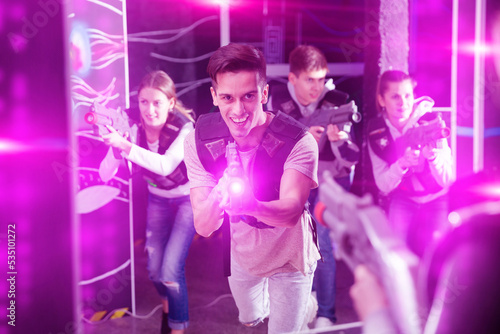 Portrait of young man with laser gun having fun on dark laser tag arena..