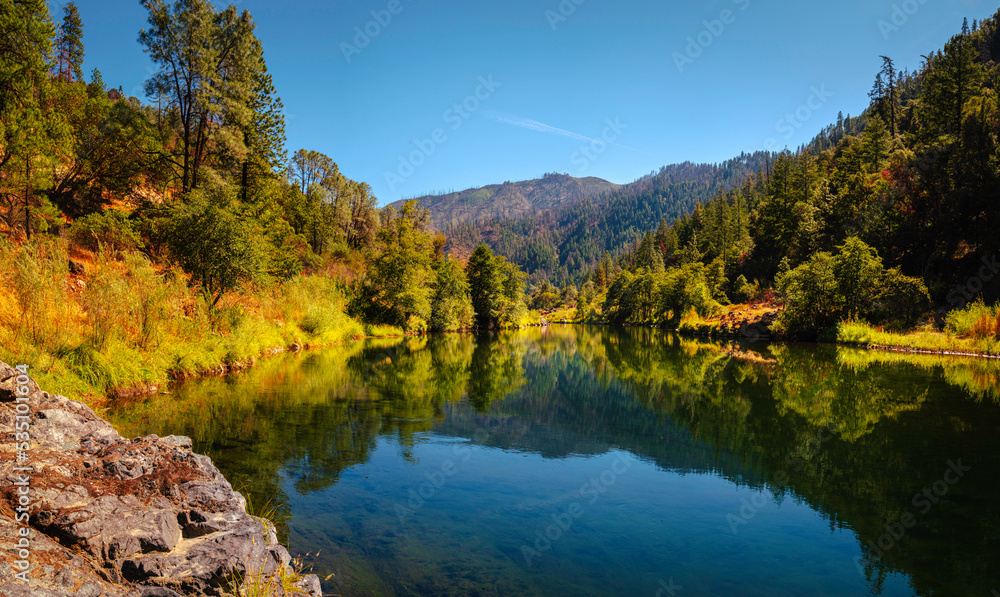 Autumn foliage and tranquil water reflections over the rocky creek on Trinity River near Del Loma, Northern California
