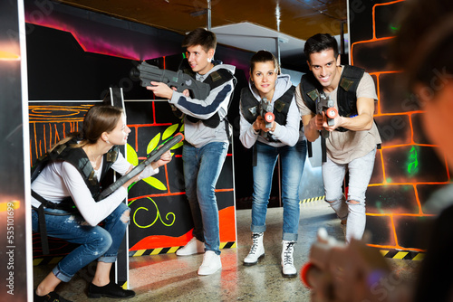 Ordinary Laser tag players young mens and womens playing in teams in dark laser tag station. High quality photo
