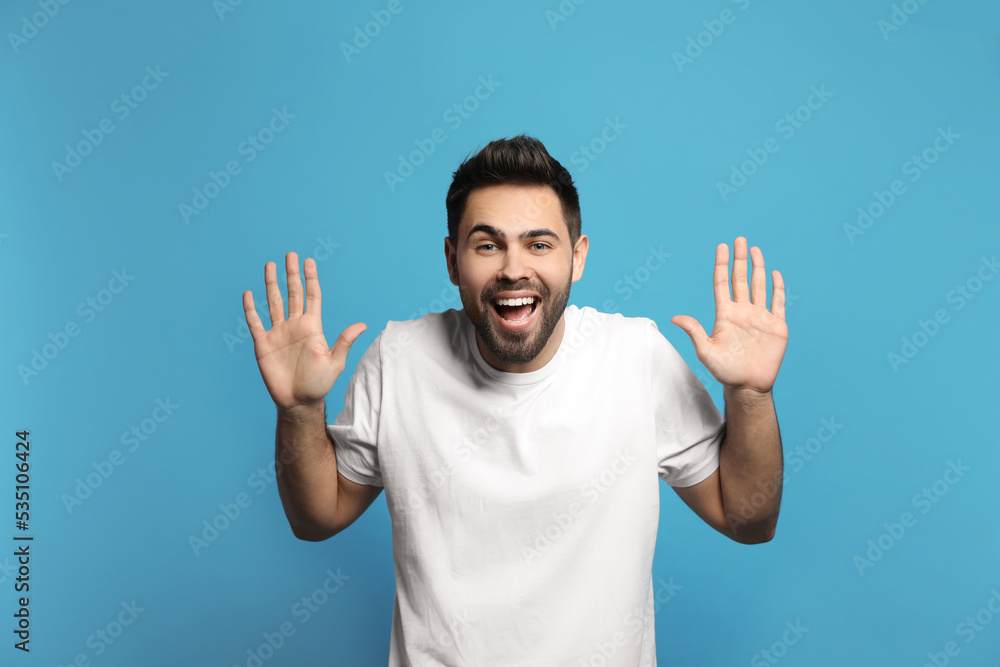 Young man laughing on light blue background. Funny joke Young man laughing on light blue background. Funny joke