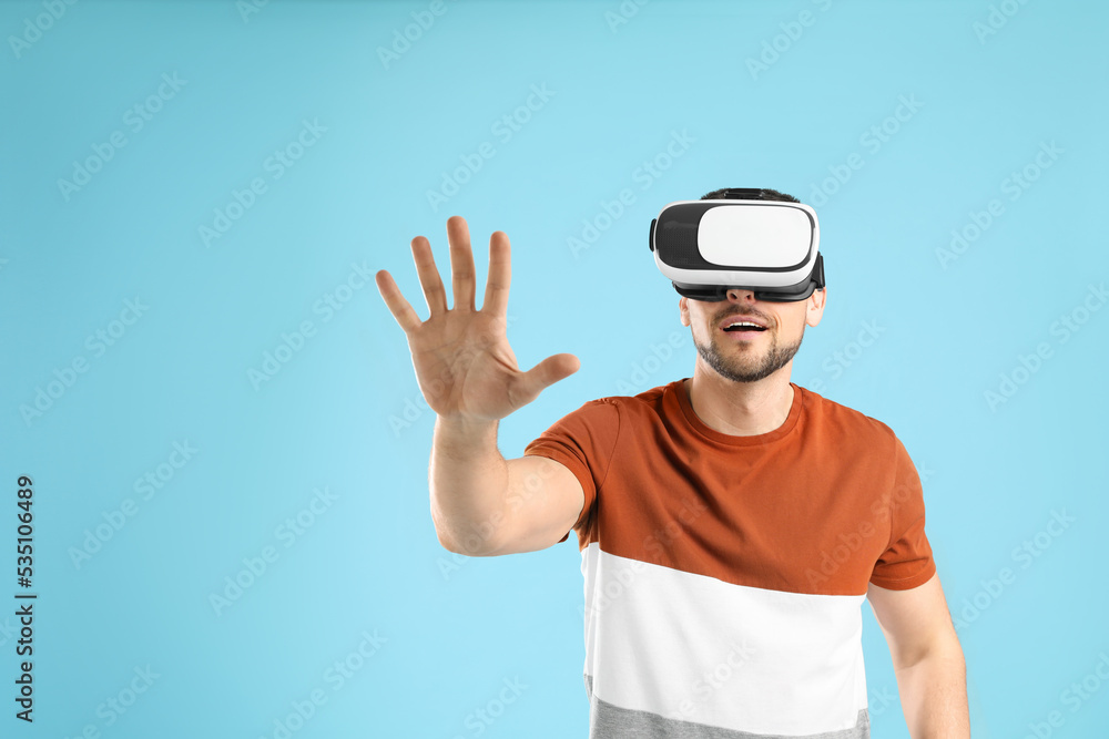 Man using virtual reality headset on light blue background Man using virtual reality headset on light blue background
