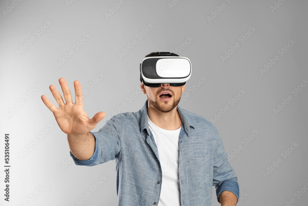 Man using virtual reality headset on grey background Man using virtual reality headset on grey background