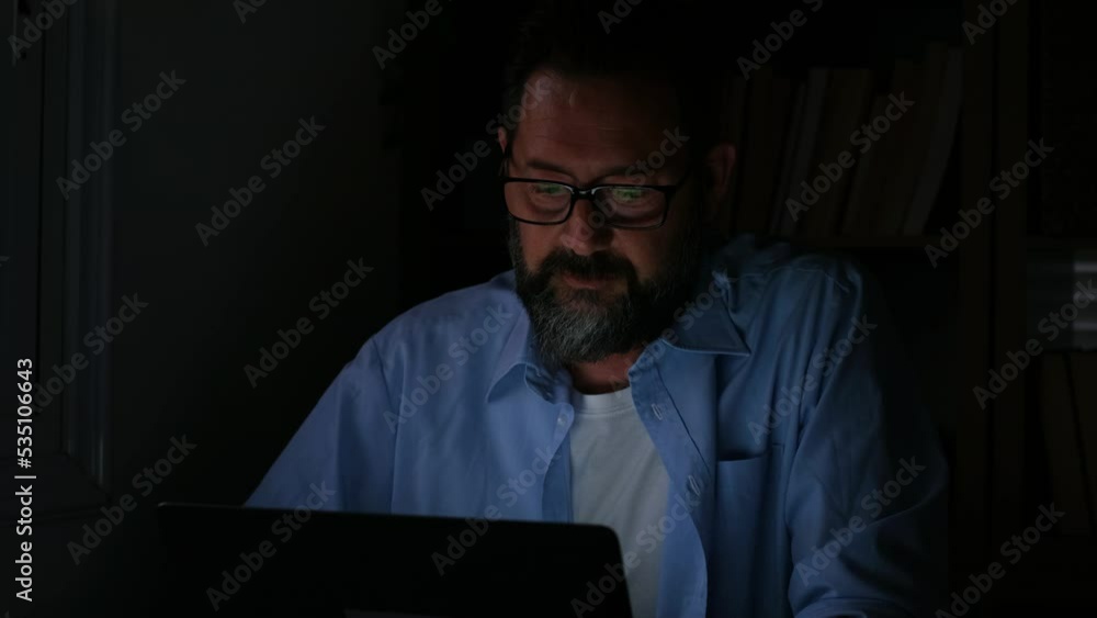 One young man using laptop and working on a computer at night at home. Businessman at job in his office One young man using laptop and working on a computer at night at home. Businessman at job in his office