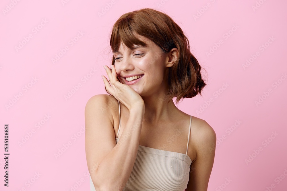 a modest, shy woman stands on a pink background and smiles pleasantly with her eyes closed and holding her hand near her head a modest, shy woman stands on a pink background and smiles pleasantly with her eyes closed and holding her hand near her head