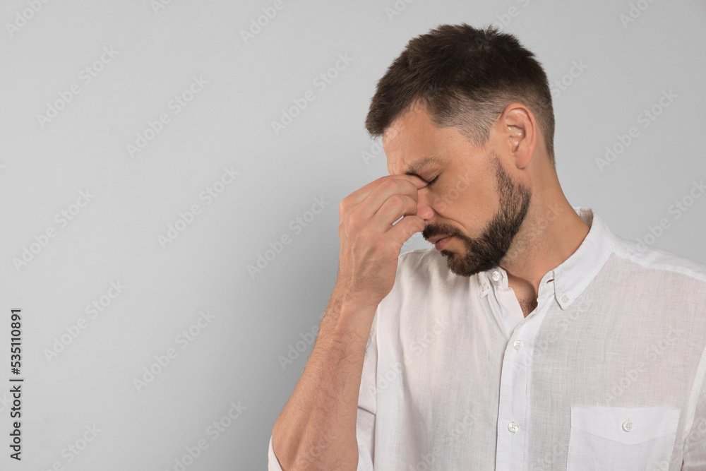 Man suffering from eyestrain on light background, space for text Man suffering from eyestrain on light background, space for text