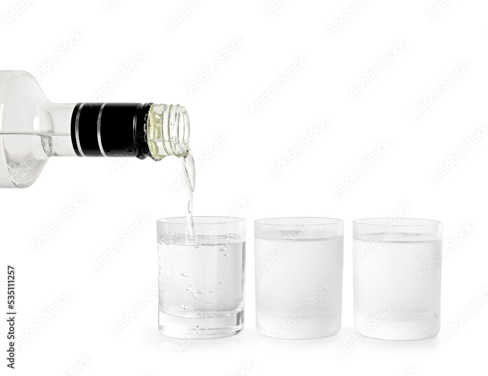 Pouring vodka from bottle in glass on white background Pouring vodka from bottle in glass on white background