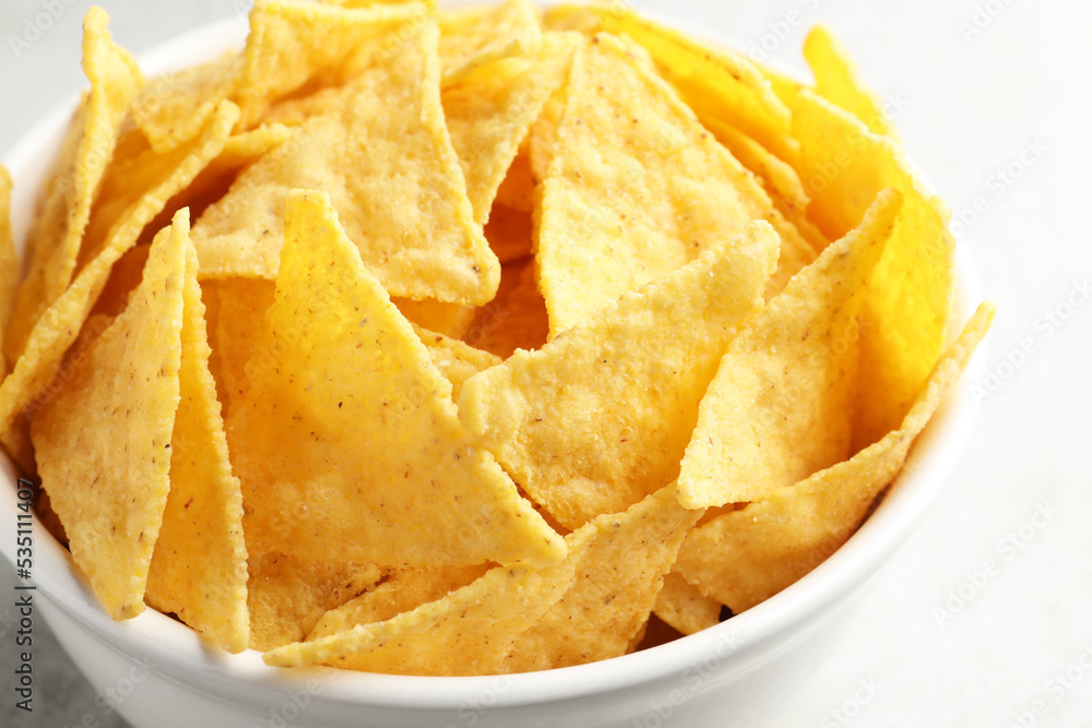 Bowl with tasty tortilla chips (nachos) on grey table, closeup Bowl with tasty tortilla chips (nachos) on grey table, closeup