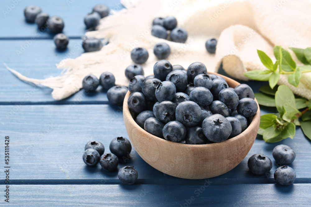 Tasty fresh blueberries and green leaves on blue wooden table, closeup Tasty fresh blueberries and green leaves on blue wooden table, closeup