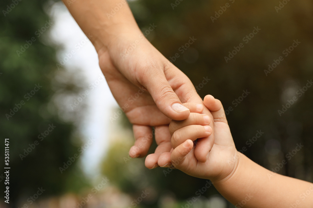 Daughter holding mother's hand in park, closeup. Happy family Daughter holding mother's hand in park, closeup. Happy family