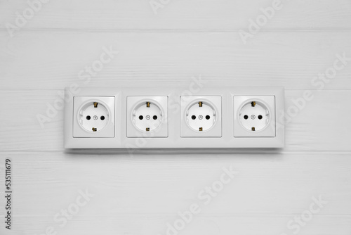 Modern plastic power socket on white wooden table, top view