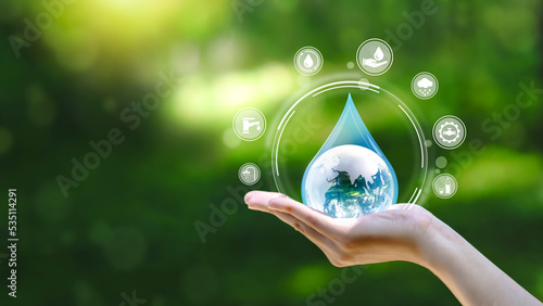 Water drop in hand against natural background in Save water concept on world water day. Conserving the environment in terms of water resources