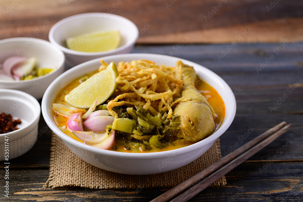 Northern Thai food (Khao Soi), Spicy curry noodles soup with chicken on wooden background, Local Thai food Northern Thai food (Khao Soi), Spicy curry noodles soup with chicken on wooden background, Local Thai food