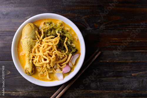 Northern Thai food (Khao Soi), Spicy curry noodles soup with chicken on wooden background, Local Thai food