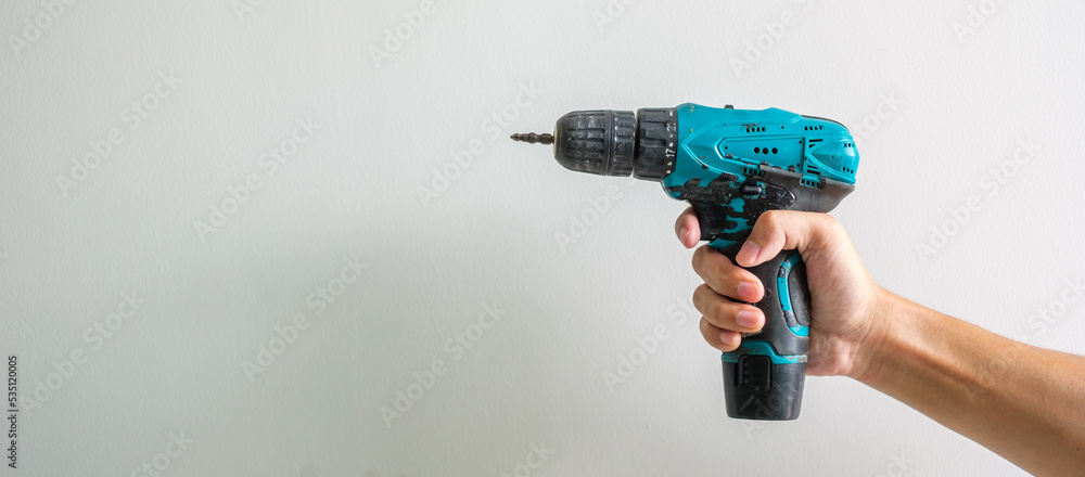 man hand holding cordless screwdriver with wall background, Carpenter working with electric screwdriver on the work man hand holding cordless screwdriver with wall background, Carpenter working with electric screwdriver on the work