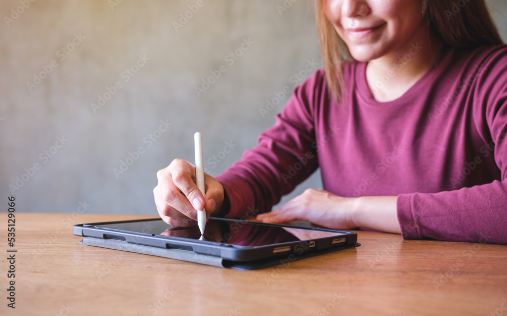 Closeup of a woman using stylus pen technology for working and writing on digital tablet screen Closeup of a woman using stylus pen technology for working and writing on digital tablet screen