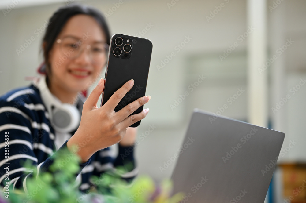 Young Asian female looking and smiling at her phone. selective focus