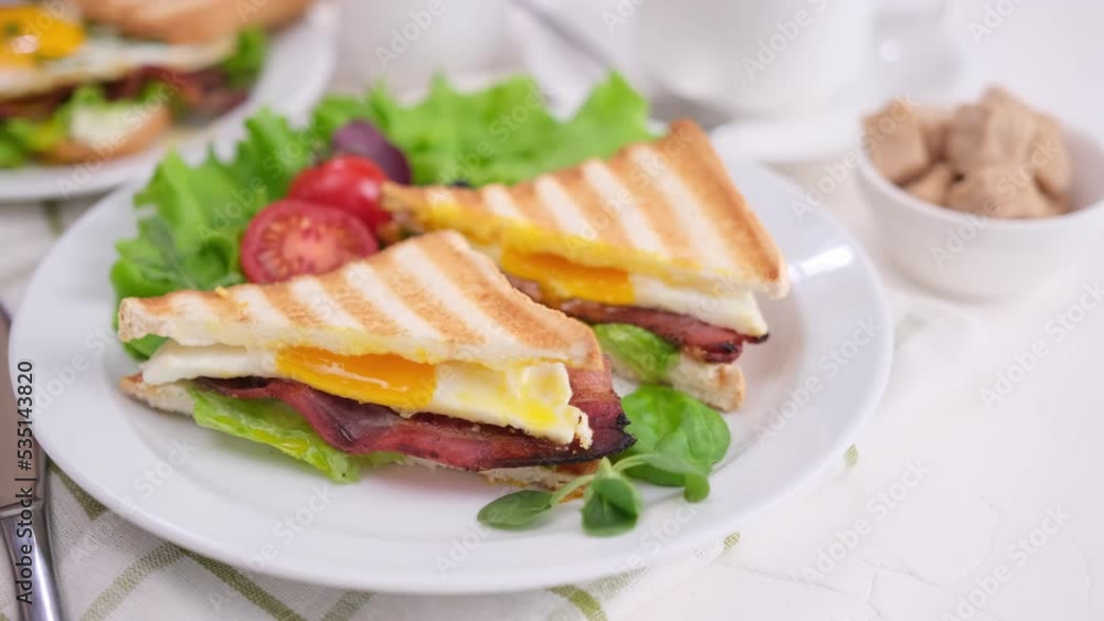 Toasts with fried bacon and eggs with salad and tomatoes on a plate Toasts with fried bacon and eggs with salad and tomatoes on a plate