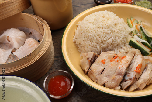 steamed Hainanese chicken rice crystal har gow transparent prawn shrimp meat stuffed dim sum in bamboo steamer green red chilli ginger soya sauce cucumber carrot on retro enamel diner plate fork spoon