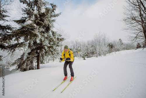 Senior man doing cross country skiing in front of snowy forest. photo