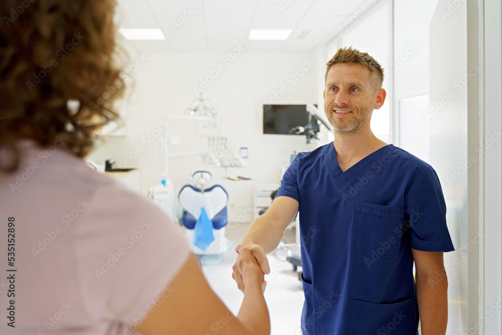 Fototapeta premium Young dentist shaking hands with the patient.