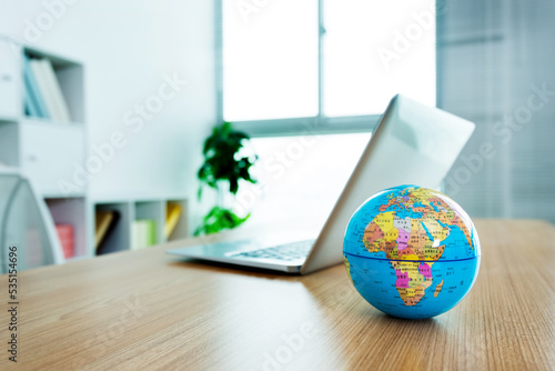 Office desk with laptop and globe photo