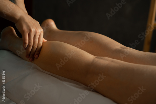 Masseur making feet massage in spa salon. Close up. Massage therapist working with patient  massaging his calves.