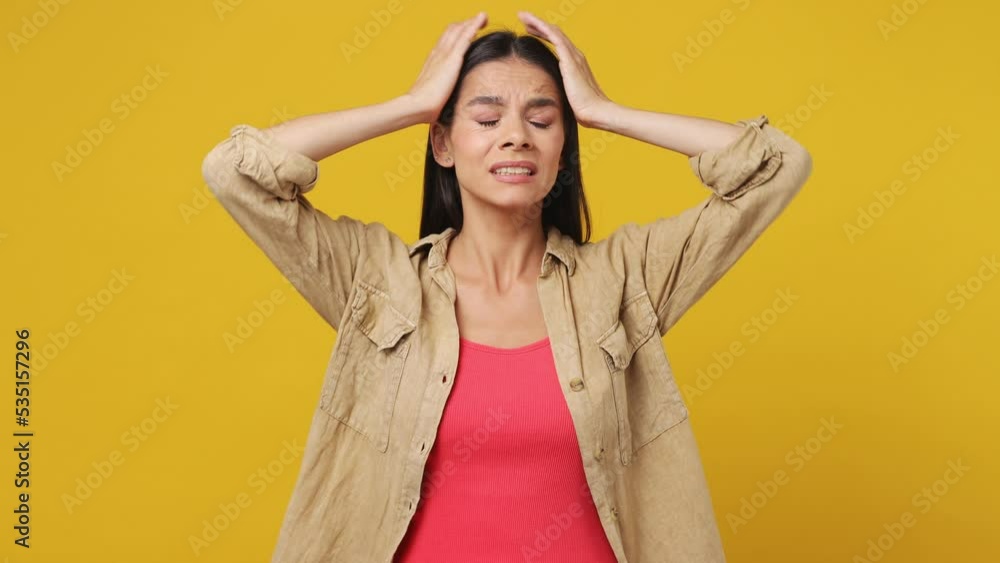 Young sad upset worried disturb displeased latin woman wear beige shirt pink t-shirt sigh suspire sithe put hands on face isolated on plain yellow background studio portrait People lifestyle concept Young sad upset worried disturb displeased latin woman wear beige shirt pink t-shirt sigh suspire sithe put hands on face isolated on plain yellow background studio portrait People lifestyle concept