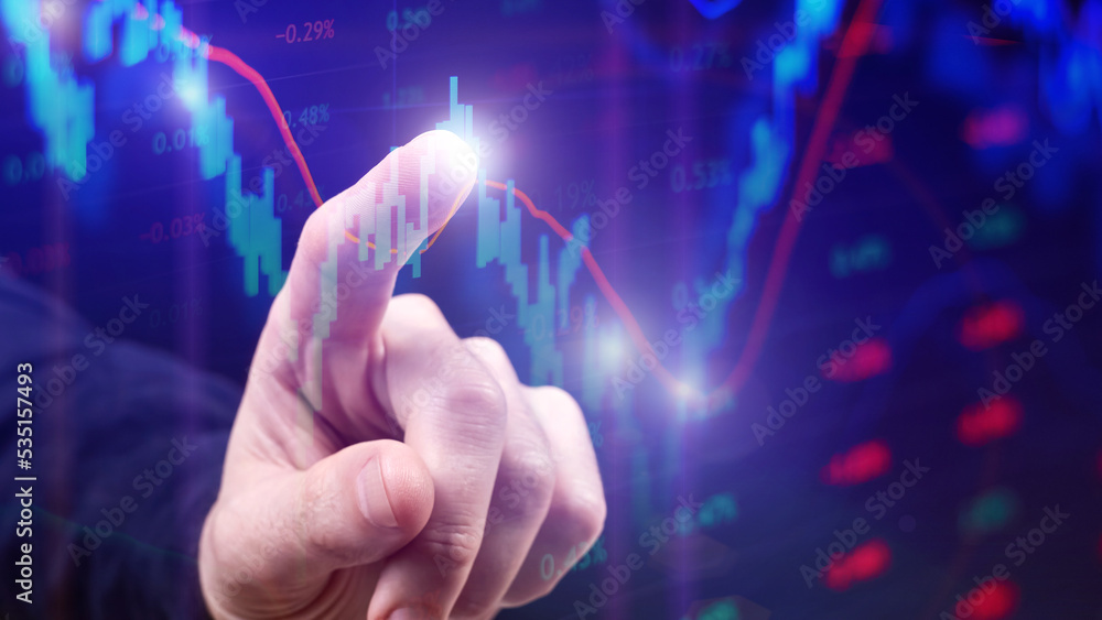 The trader points his finger at the stock chart on the monitor The trader points his finger at the stock chart on the monitor