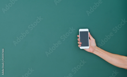 Hand holding smart phone in front of blackboard