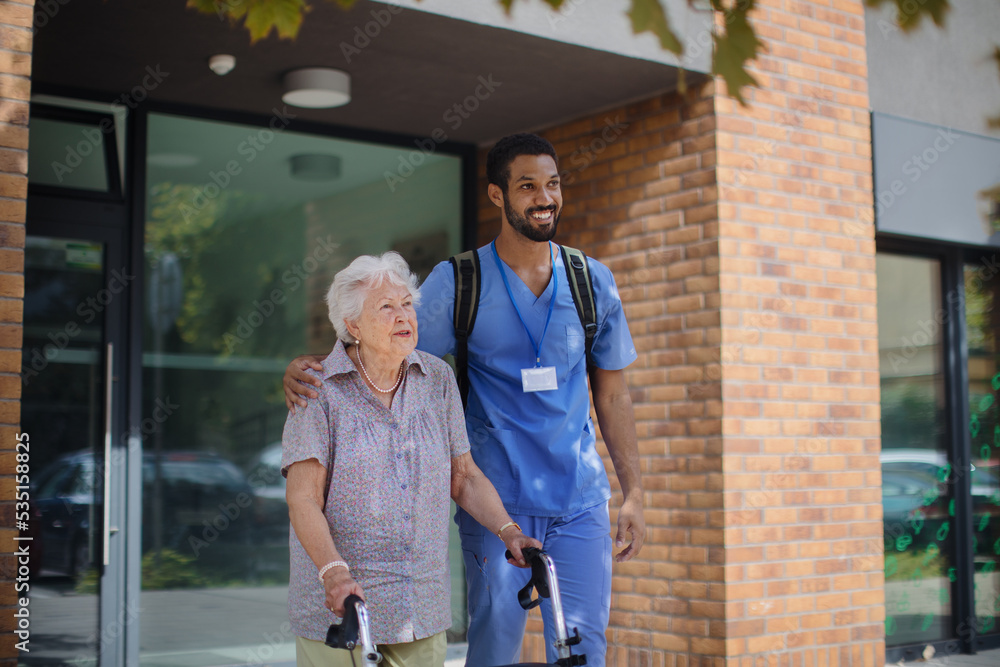 Caregiver walking with senior woman client in front of nurishing home. Caregiver walking with senior woman client in front of nurishing home.