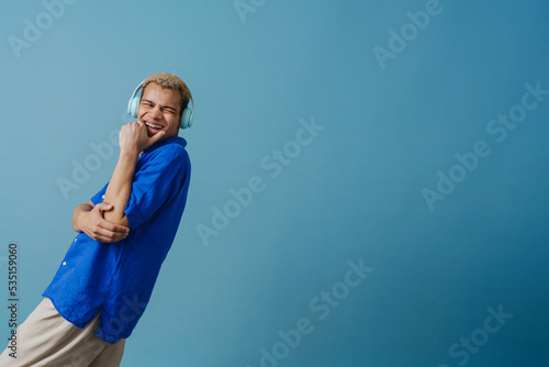 Blonde young man in headphones laughing while listening music