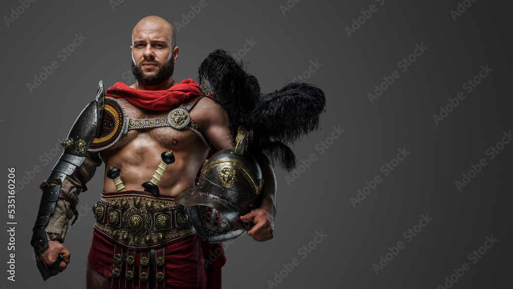 Obraz premium Shot of serious roman gladiator with naked torso and plumed helmet isolated on grey background.