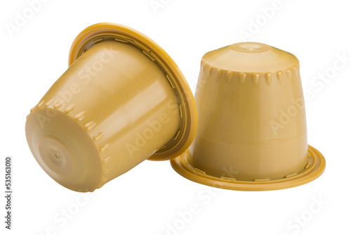 Two yellow capsules with ground coffee, for a capsule coffee machine, on a white background, one capsule is overturned, isolate photo
