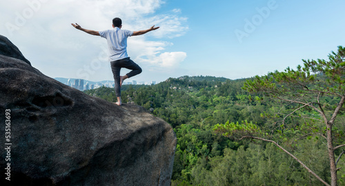 Young man doing yoga on mountain peak