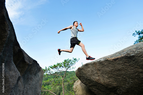 Young man jumping over the cliff