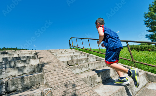 Rear view of young boy running up on steps