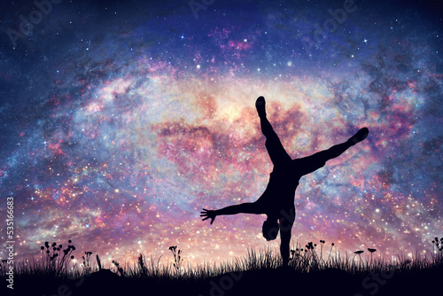 Happy man doing cartwheel on night sky with nebula and stars