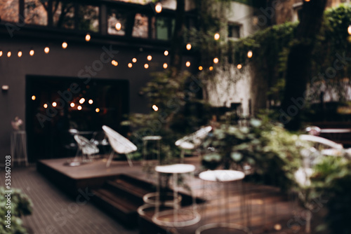 Blurred background of outdoor restaurant with abstract bokeh light. Outdoor cafe with tables and chairs. Defocused Background