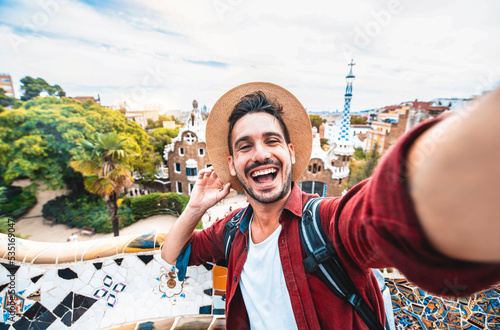 Happy tourist take selfie self-portrait with smartphone in Park Guell, Barcelona, Spain - Smiling man on vacation looking at camera - Holidays and travel concept photo